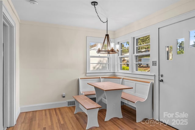 dining area with breakfast area, light wood-type flooring, crown molding, and an inviting chandelier