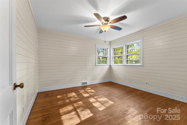 unfurnished room with wooden walls, dark hardwood / wood-style flooring, and ceiling fan