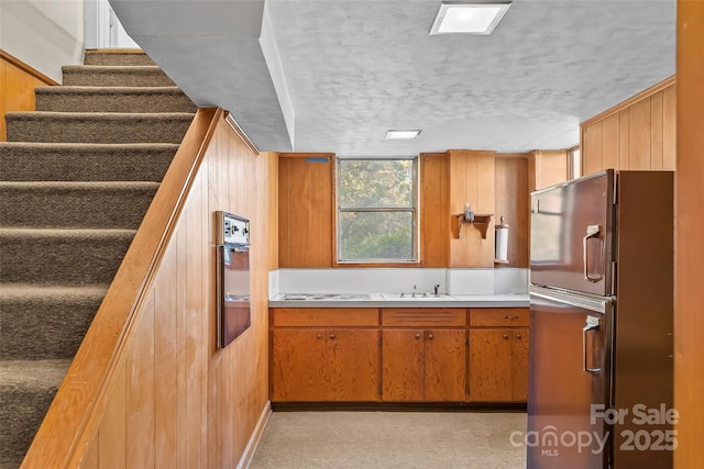 kitchen with refrigerator, wall oven, wood walls, and sink