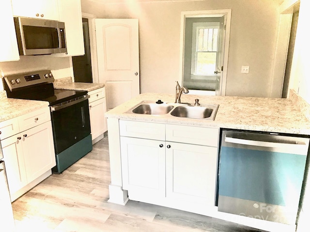 kitchen featuring light hardwood / wood-style floors, appliances with stainless steel finishes, white cabinets, light stone counters, and sink