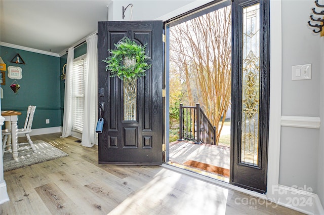 entryway with plenty of natural light, ornamental molding, and light hardwood / wood-style flooring