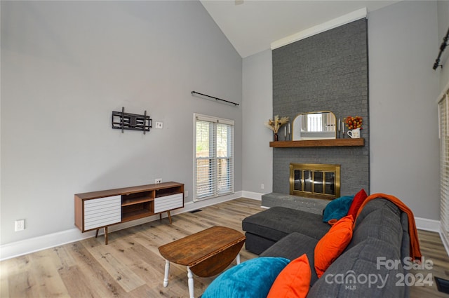 living room with a brick fireplace, high vaulted ceiling, and hardwood / wood-style flooring