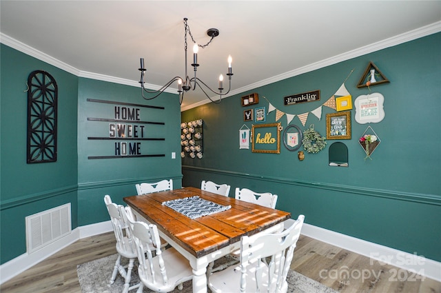 dining area with hardwood / wood-style floors, an inviting chandelier, and ornamental molding