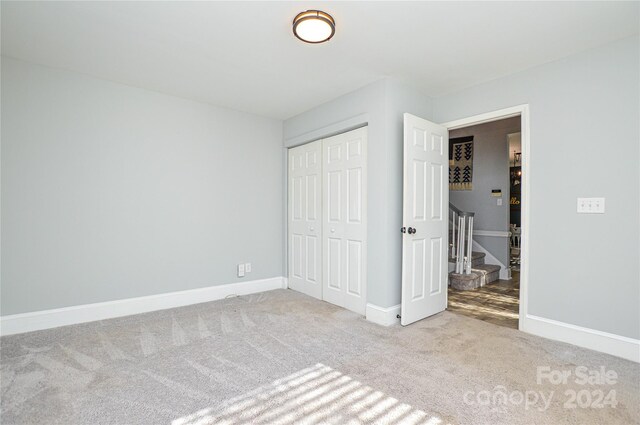 unfurnished bedroom featuring light carpet and a closet