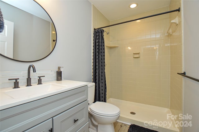 bathroom featuring curtained shower, hardwood / wood-style floors, vanity, and toilet