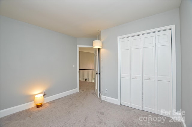 unfurnished bedroom with light carpet and a closet