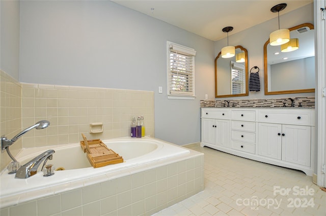 bathroom with tile patterned flooring, vanity, and tiled bath