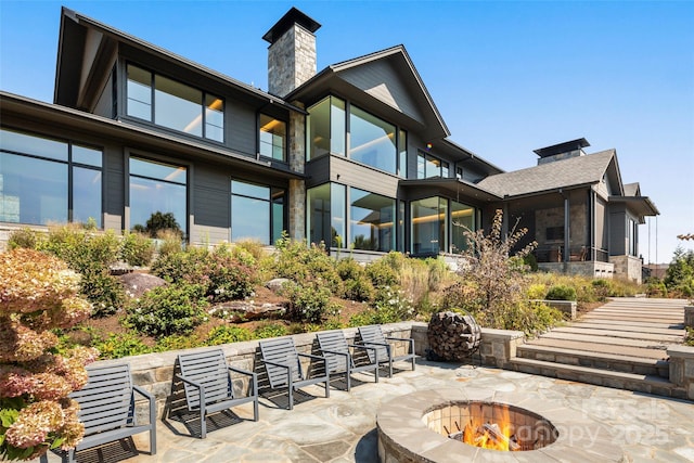 rear view of property featuring a patio and an outdoor fire pit