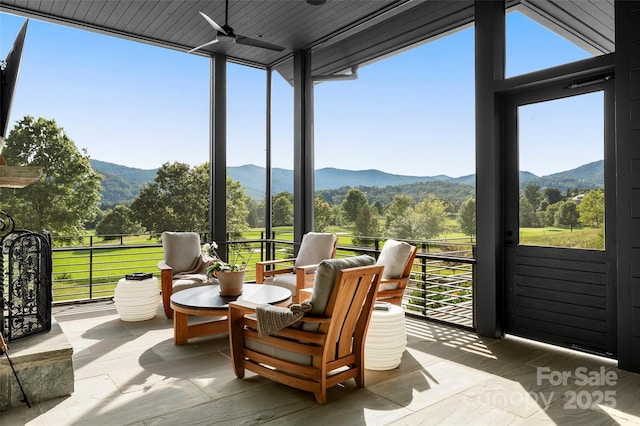 sunroom featuring ceiling fan and a mountain view