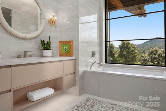 bathroom featuring tile walls, a mountain view, tile patterned floors, a tub, and vanity