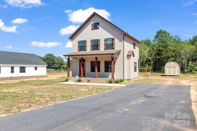 view of property with a porch, a storage unit, and a front lawn