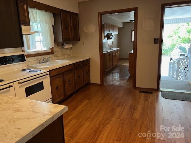 kitchen with a healthy amount of sunlight, white range with electric cooktop, range hood, and hardwood / wood-style floors