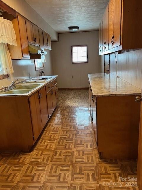 kitchen with a textured ceiling, light parquet floors, and sink