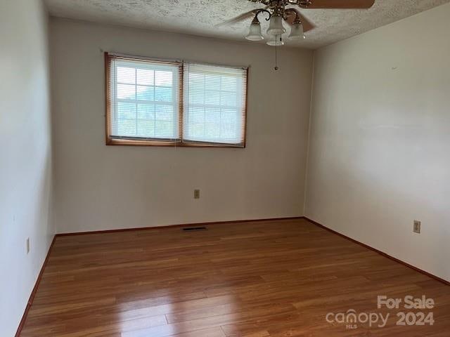 empty room featuring ceiling fan, hardwood / wood-style flooring, and a textured ceiling