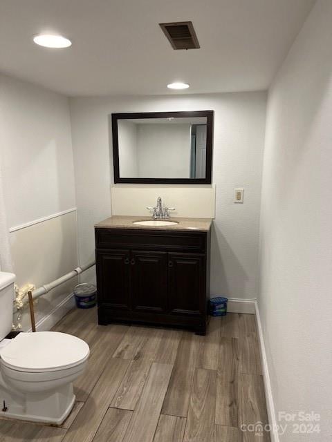 bathroom featuring vanity, toilet, and hardwood / wood-style flooring