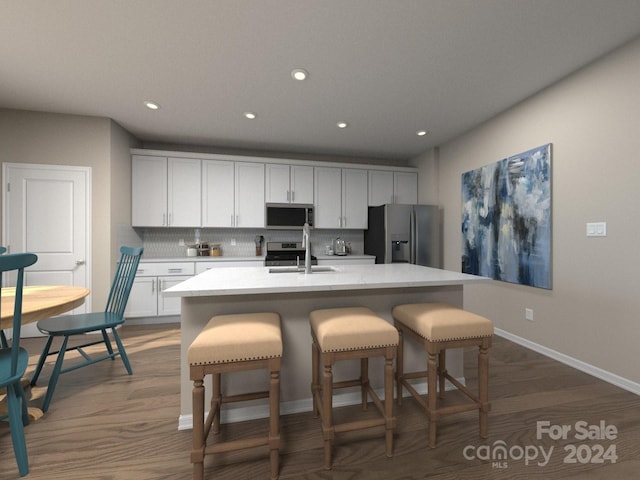 kitchen with an island with sink, decorative backsplash, dark hardwood / wood-style flooring, white cabinetry, and appliances with stainless steel finishes