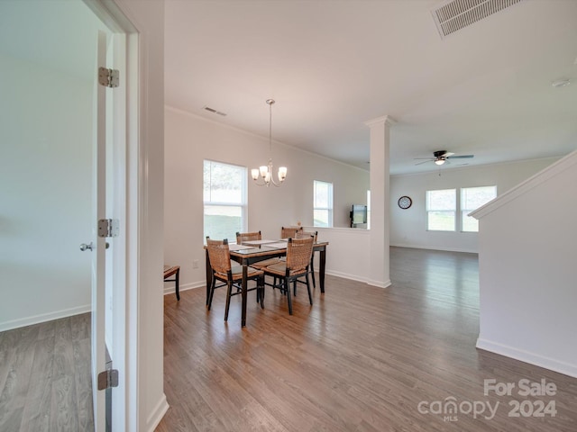 dining room featuring hardwood / wood-style flooring, ceiling fan with notable chandelier, plenty of natural light, and ornate columns