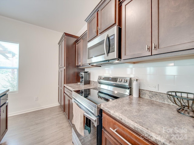 kitchen with backsplash, stainless steel appliances, crown molding, and light hardwood / wood-style floors