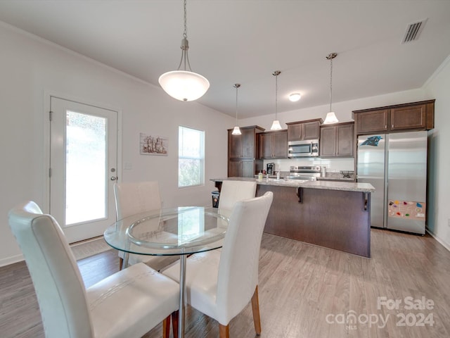 dining space with light wood-type flooring and crown molding