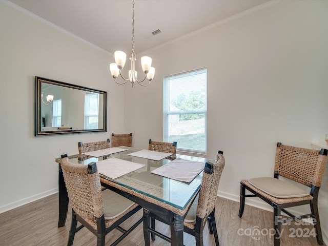 dining area featuring wood-type flooring, ornamental molding, and a chandelier