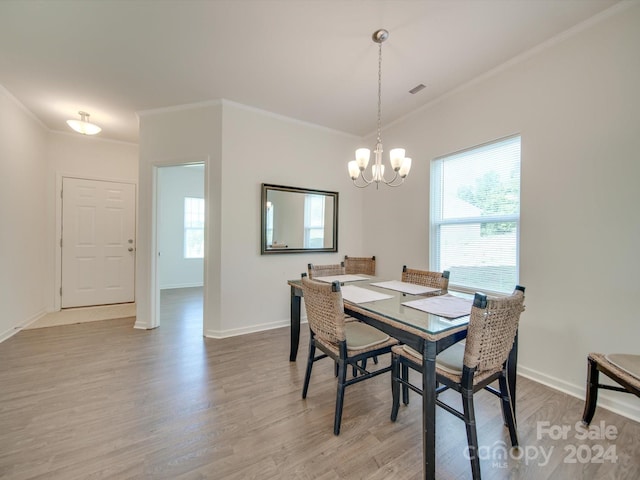 dining room with crown molding, an inviting chandelier, and light hardwood / wood-style flooring