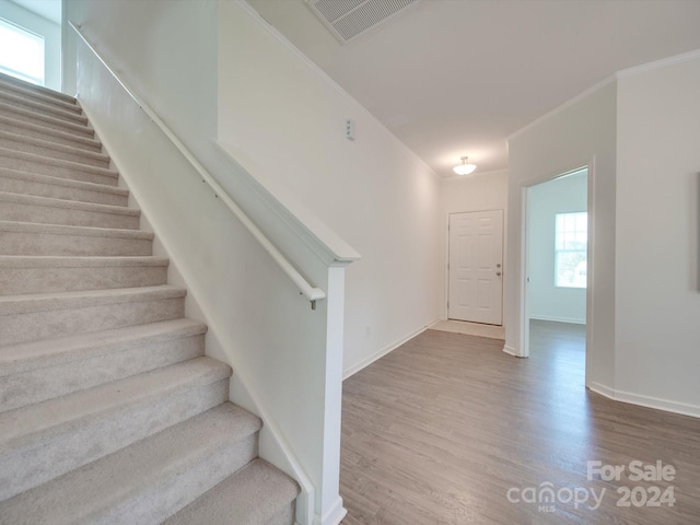 stairway featuring ornamental molding, hardwood / wood-style floors, and plenty of natural light