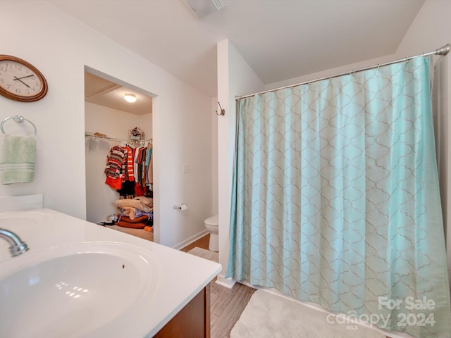 bathroom with hardwood / wood-style floors, a shower with curtain, vanity, and toilet