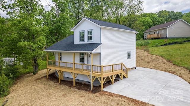 rear view of house featuring a wooden deck and a lawn