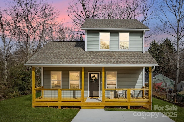 view of front of home featuring a porch, a front lawn, and a shingled roof