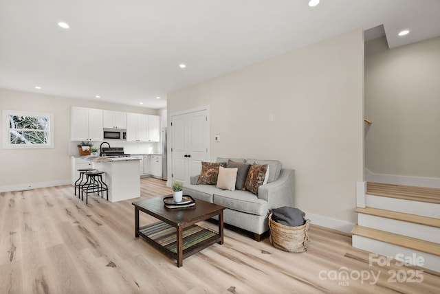 living room with light wood-style floors, recessed lighting, baseboards, and stairs