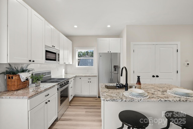 kitchen featuring appliances with stainless steel finishes, white cabinets, and light stone countertops