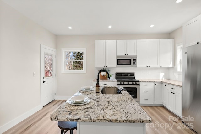 kitchen featuring stainless steel appliances, a center island, and white cabinetry