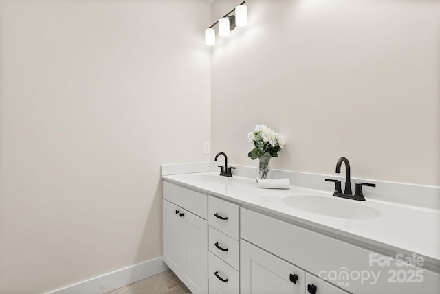 bathroom featuring double vanity, wood finished floors, a sink, and baseboards