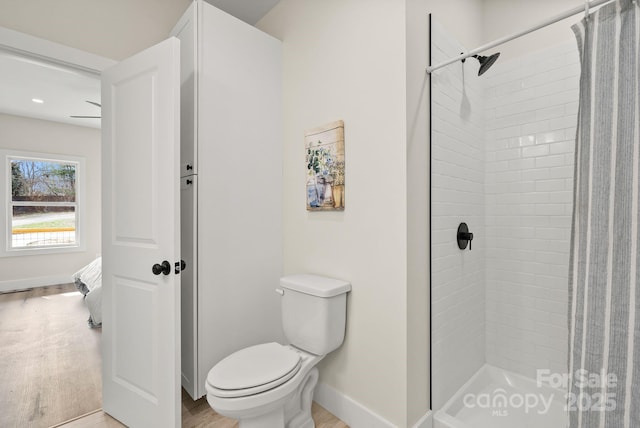 bathroom featuring baseboards, toilet, wood finished floors, ensuite bathroom, and a shower stall