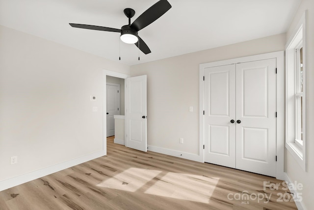 unfurnished bedroom with a closet, baseboards, ceiling fan, and light wood finished floors