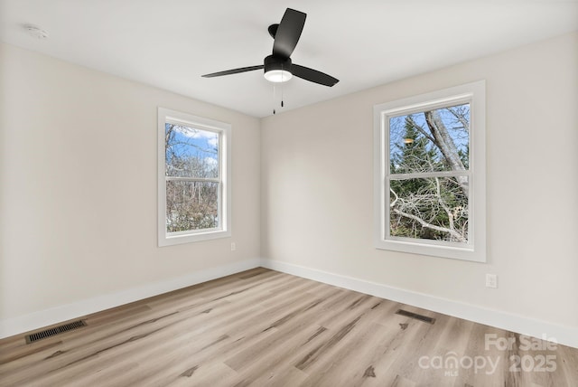 empty room featuring visible vents, ceiling fan, light wood finished floors, and baseboards