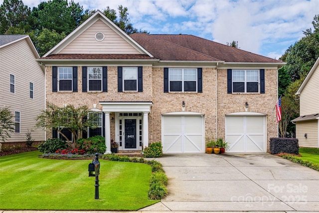 view of front of house featuring a front lawn, driveway, roof with shingles, an attached garage, and brick siding