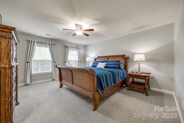 carpeted bedroom featuring a ceiling fan, visible vents, and baseboards