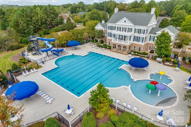 pool with a water slide, a patio, and fence