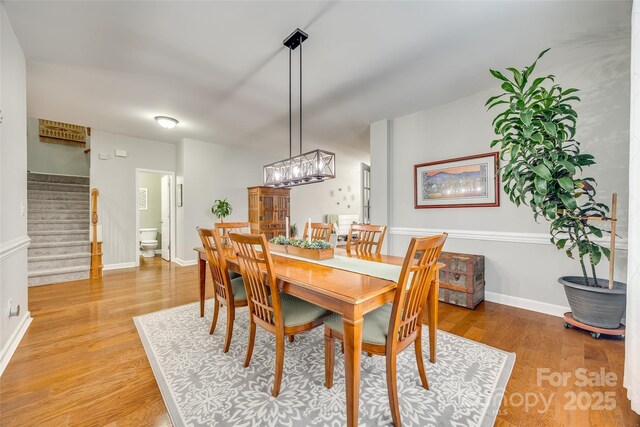 dining room featuring light wood-type flooring, stairway, and baseboards