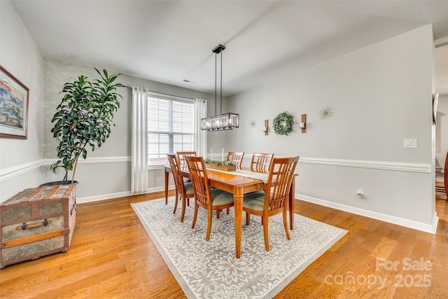 dining room featuring an inviting chandelier, light wood-style flooring, and baseboards