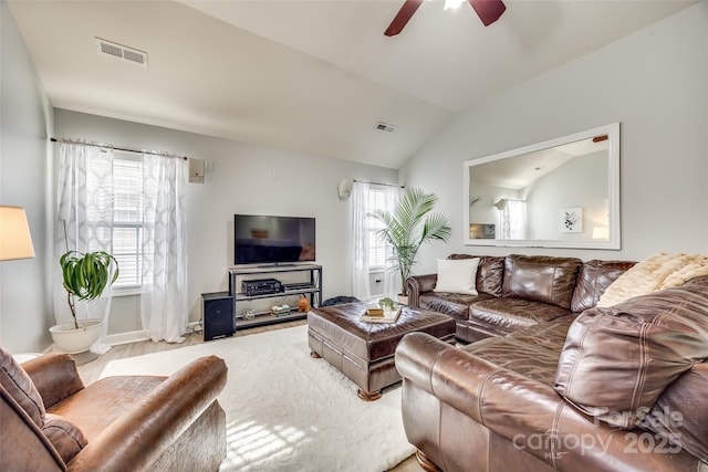 living room featuring a wealth of natural light, visible vents, and vaulted ceiling