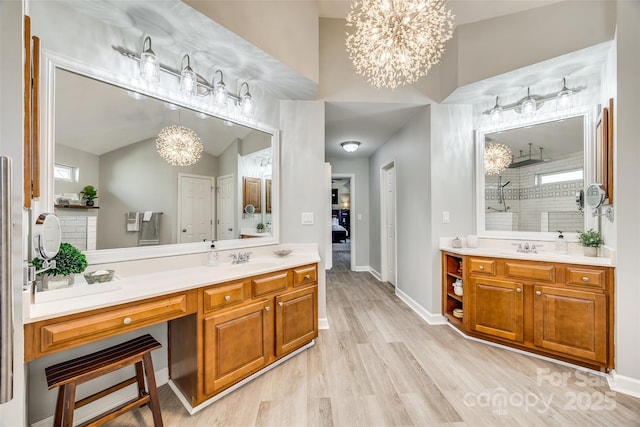 full bath with vanity, wood finished floors, a healthy amount of sunlight, a walk in shower, and a notable chandelier