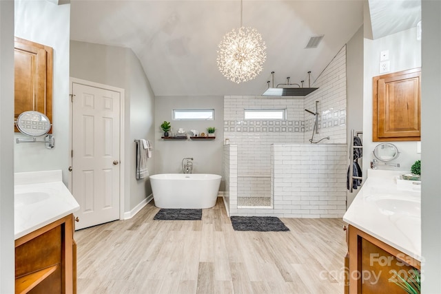 bathroom featuring lofted ceiling, two vanities, a walk in shower, and wood finished floors