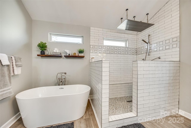 full bathroom featuring baseboards, a walk in shower, a freestanding bath, and wood finished floors