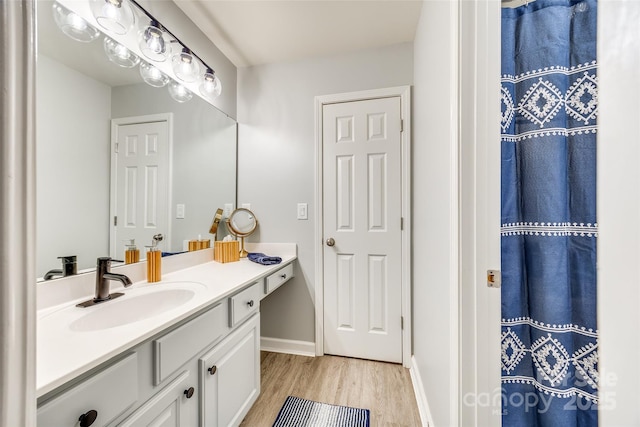 full bathroom with vanity, a shower with shower curtain, wood finished floors, and baseboards