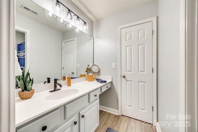 full bath featuring visible vents, baseboards, wood finished floors, and vanity