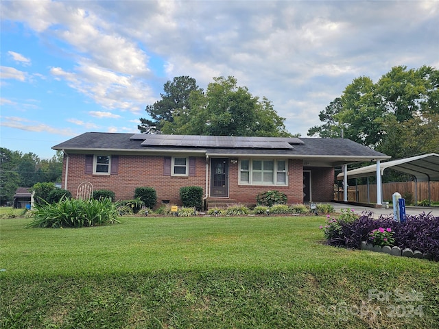 ranch-style home with a front yard, solar panels, and a carport