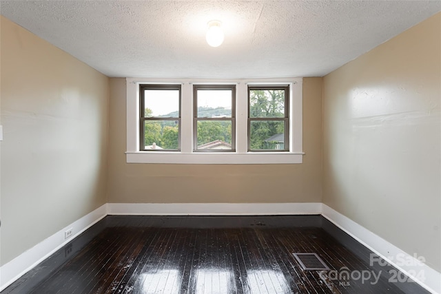 unfurnished room featuring wood-type flooring and a textured ceiling