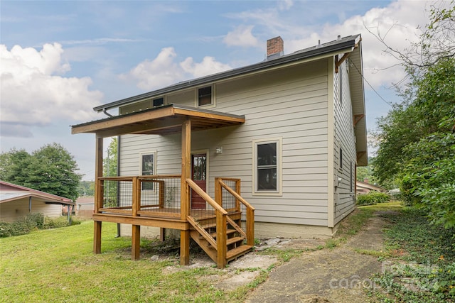 back of house featuring a wooden deck and a lawn